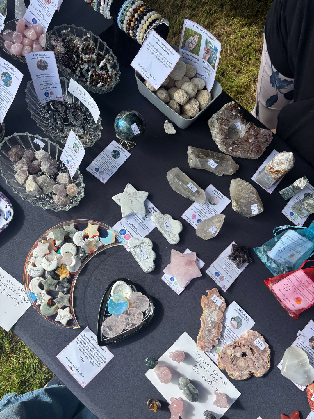 An overhead view of a crystal market stall display table filled with raw stones, bracelets, and carvings for a beginner's guide on choosing your first crystals.