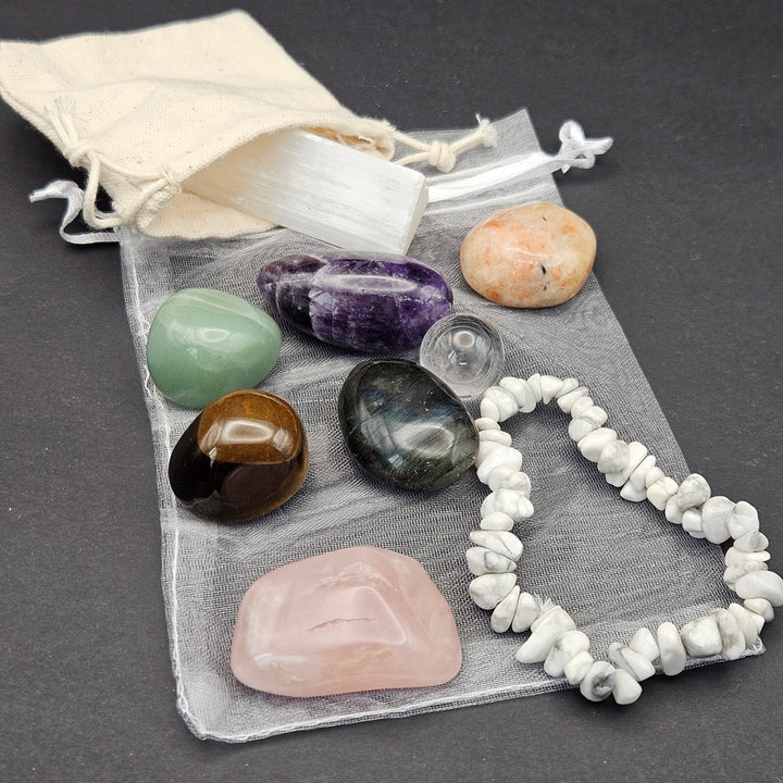 Everyday Bracelet &amp; Crystal Set featuring a white Howlite chip bracelet, polished Amethyst, Rose Quartz, Green Aventurine, Tiger Eye, Sunstone, Labradorite, a Clear Quartz mini sphere, and a raw Selenite stick with cotton and organza storage pouches. 