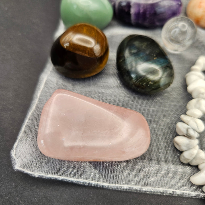 Everyday Bracelet and 7 Crystal Tumbles Kit with a Howlite bracelet, natural stones, a raw Selenite stick, and a soft drawstring pouch. 