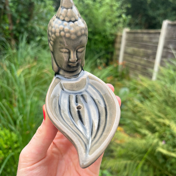 A small Buddha head incense burner with a leaf-shaped base, held in a person&