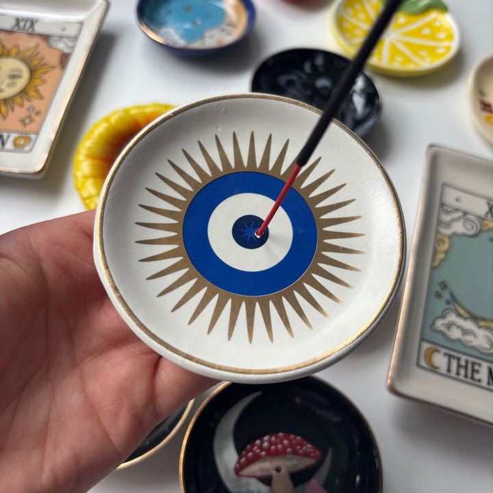 Decorative All Seeing Eye Incense Stick Holder held by a hand, surrounded by tarot cards and other decorative items.
