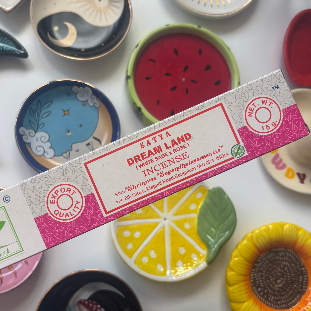 Sativa Dream Land incense packaging held over decorative plates with various designs.