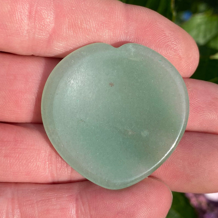 A small, smooth, Green Aventurine Heart Worry Stone Crystal held in a person&