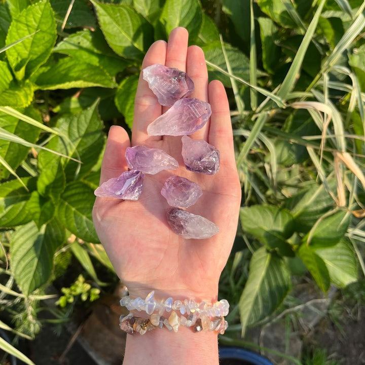 Mini Amethyst Rough Irregular Points being held in a hand in a garden on a bright sunny day