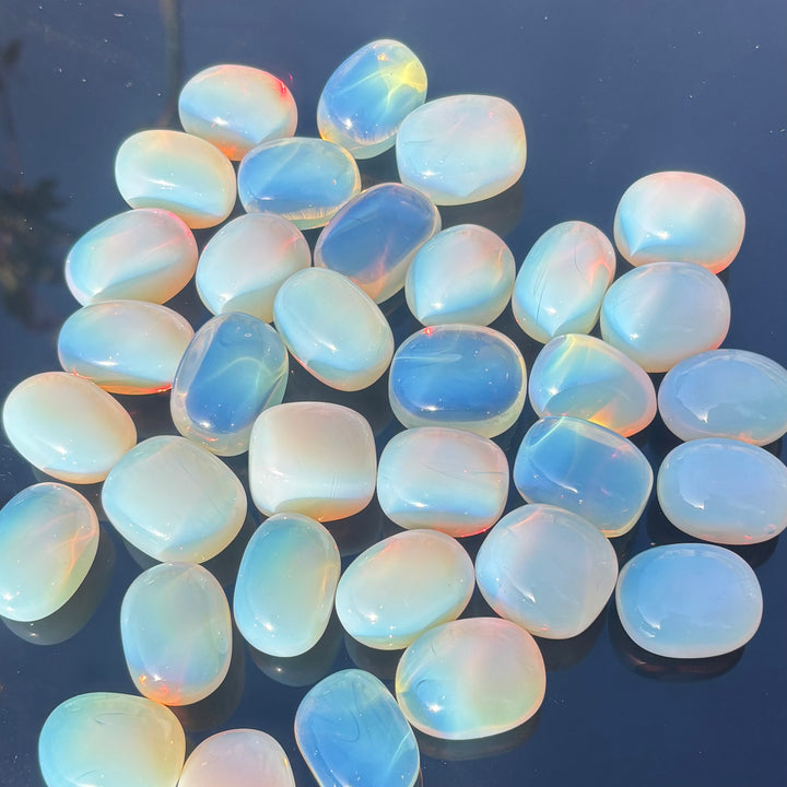 A collection of opalite tumbles stones crystals displayed on a person&