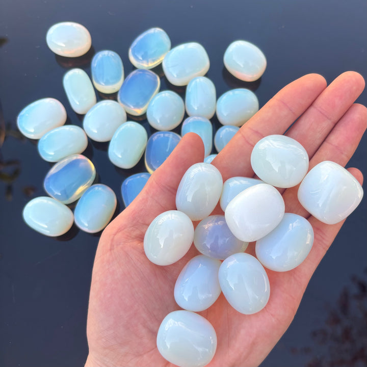 A collection of opalite tumble stone crystals displayed on a person&