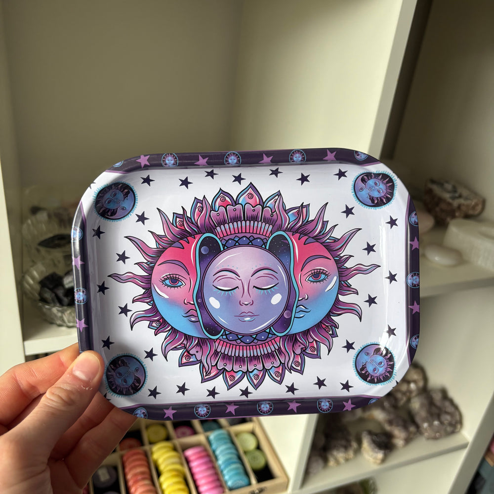 Decorative tray with sun and moon design held by a hand against a neutral background.