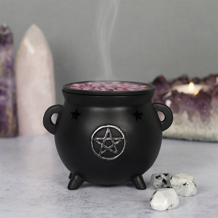 Black ceramic incense burner with purple interior held in a hand against a blurred indoor background.