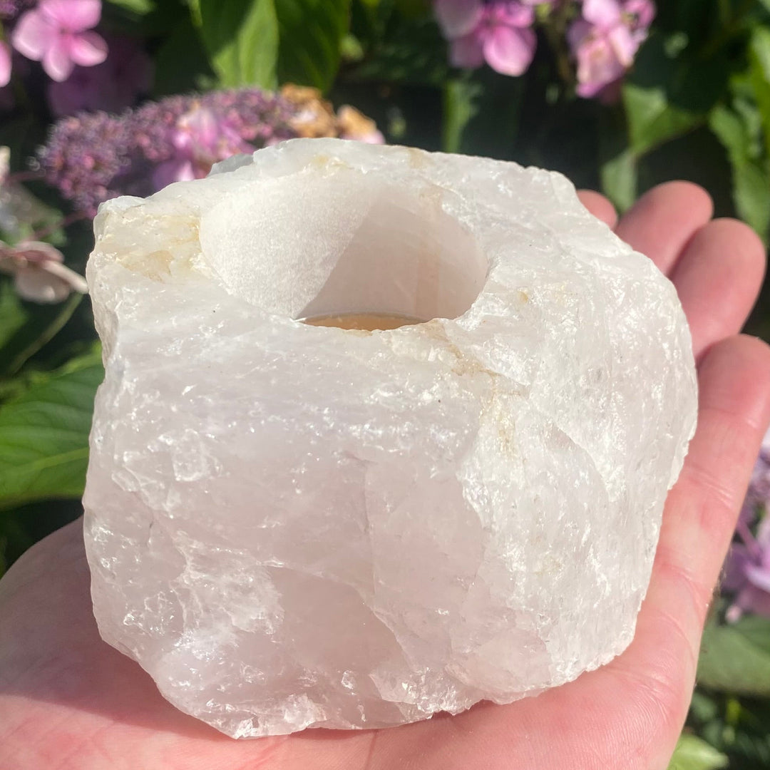 Rose Quartz Crystal Tea Light Holder held in a hand in a garden on a bright sunny day