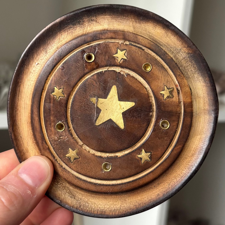 Hand holding a wooden Star Incense Stick Holder against a blurred indoor background