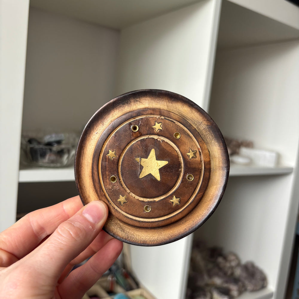 Hand holding a wooden Star Incense Stick Holder against a blurred indoor background