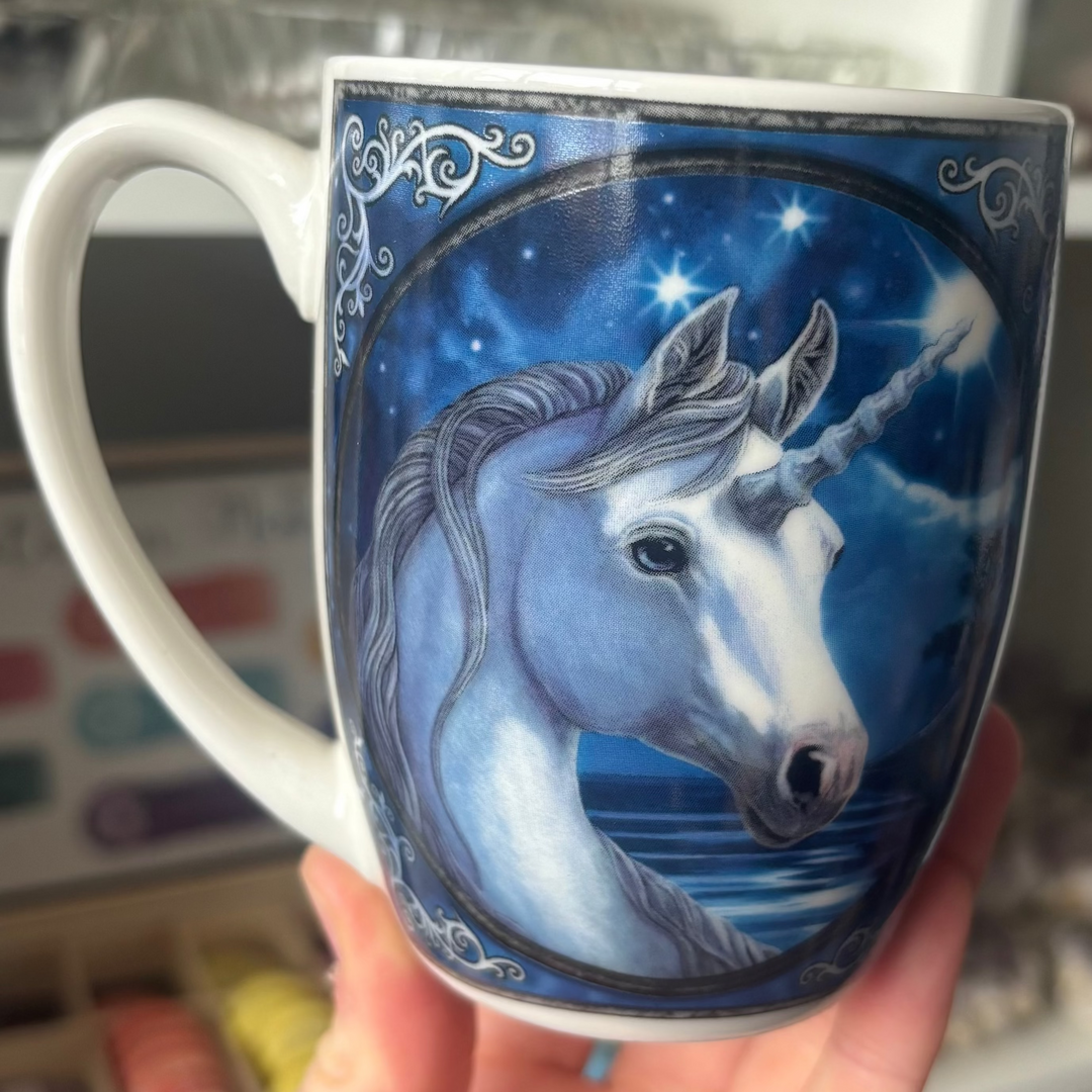 Mug with unicorn design held in front of a blurred indoor background