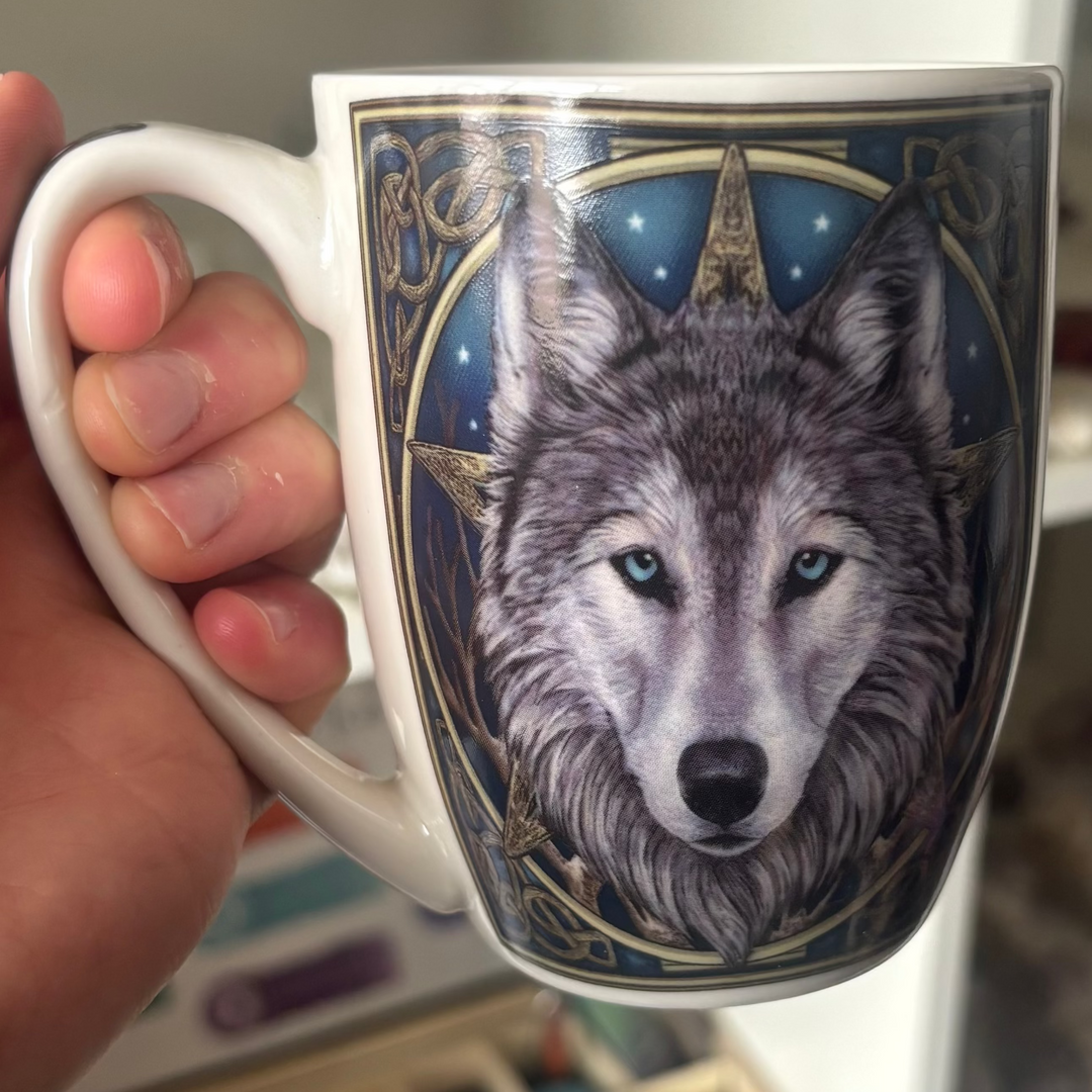 Mug with wolf design held by a hand, blurred background