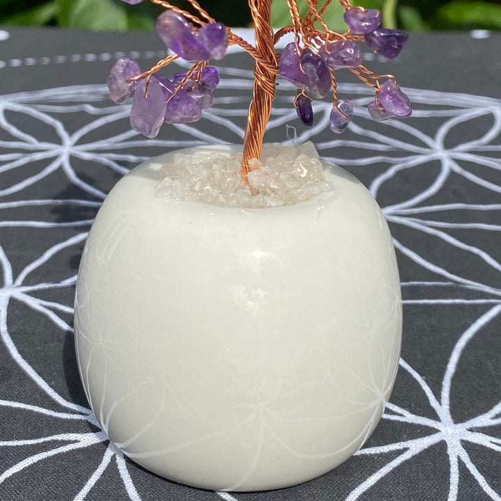 A clean profile shot focusing directly on the 4cm diameter smooth round quartz base supporting the amethyst crystal tree. The minimalist styling illustrates a comforting home wellness gift that naturally dissolves worries and anchors absolute peace into any environment.