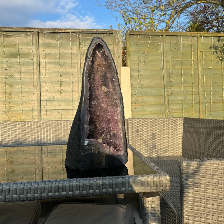 An amethyst statement piece displayed on a garden chair outdoors. 