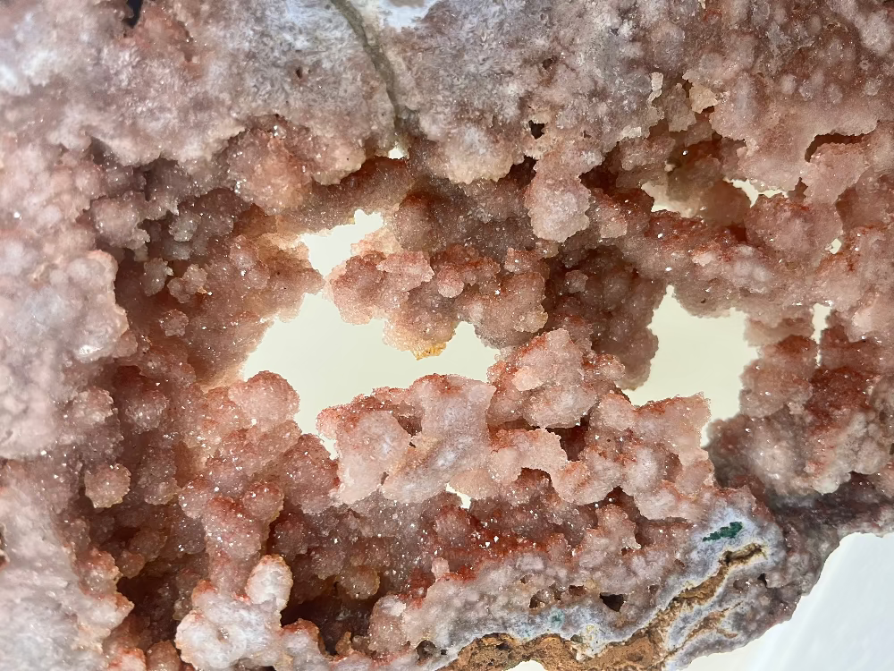 Close-up of a raw pink druzy crystal cluster geode showing intricate, sparkling mineral formations used for intentional healing and personal growth.