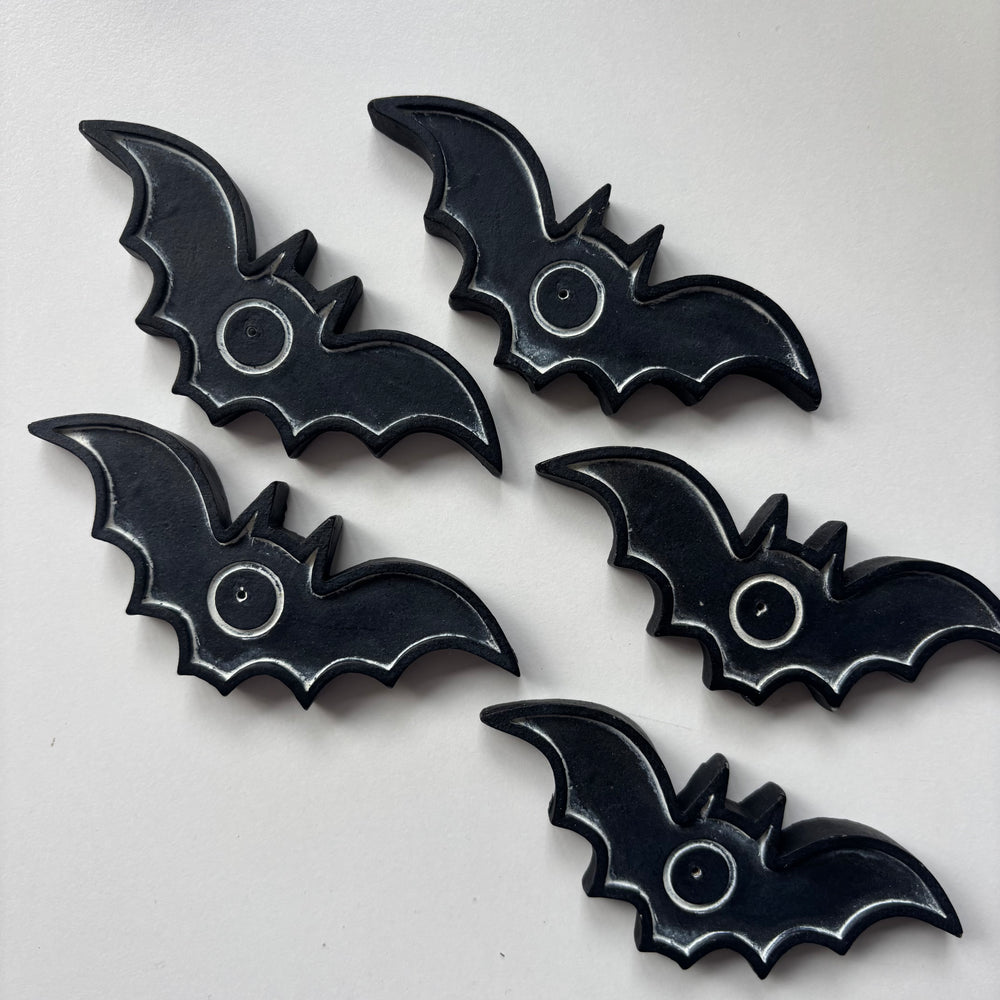 A high-angle flat lay shot showcasing a matching collection of five black resin bat incense trays spread across a bright white background. The structured alignment highlights the uniform wing dimensions and stylized spooky contours of the ritual pieces.
