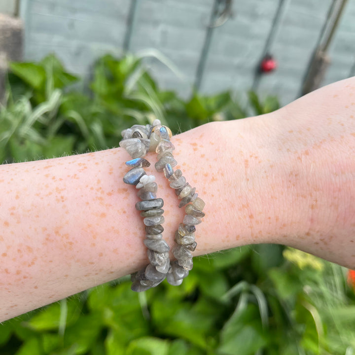A person displaying a lightweight, flexible grey labradorite stretchy chip bracelet on their wrist outside, demonstrating a comfy everyday aura designed to keep your personal energy secure during periods of transformation.
