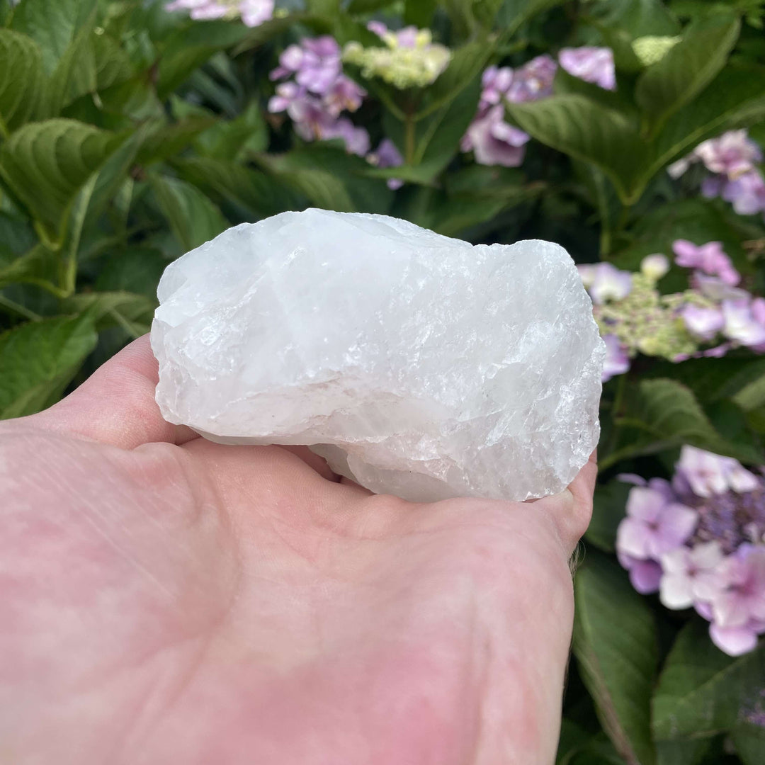 A front-facing view of the raw White Quartz cluster held flat in an open palm. The close-up shot displays its misty internal cloud zones, complex crystalline layers, and unique mineral inclusion lines ideal for intentional meditation rituals.