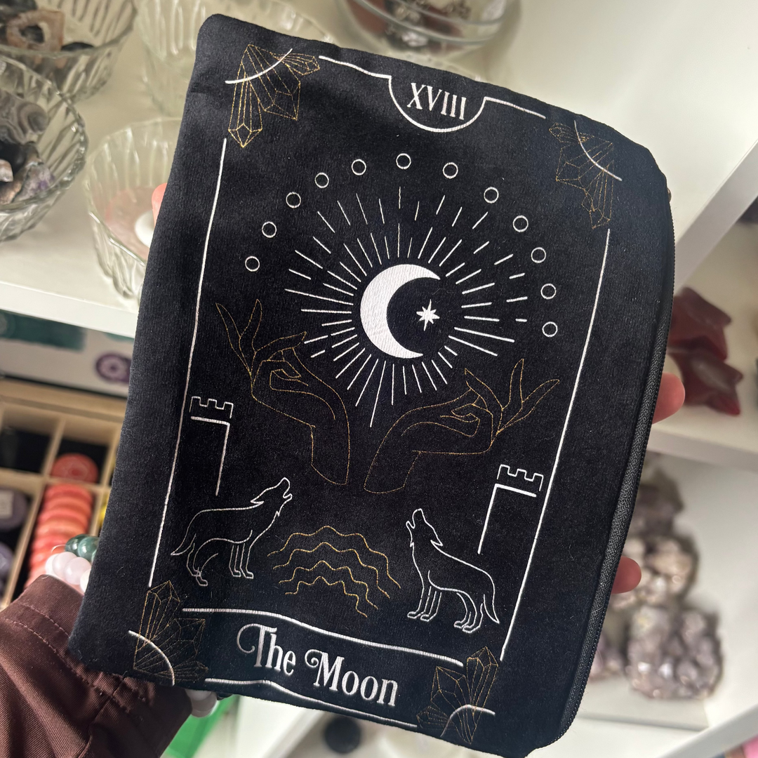 A black velvet tarot card bag featuring a white and gold screen-printed design of The Moon tarot card with wolves howling at a crescent moon