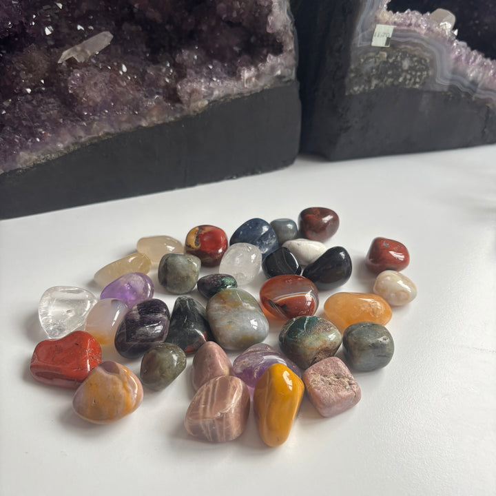 A high-angle view looking down at a scattered pile of colourful pocket tumble stones from the imperfect collection, displaying their unique shapes and natural markings designed to bring an intuitive vibe to your home.
