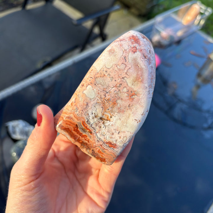 An alternative angled shot of the weighted Cotton Candy Agate gemstone slice held flat in an open hand, perfect for a cosy bedside table or a home altar centrepiece layout.