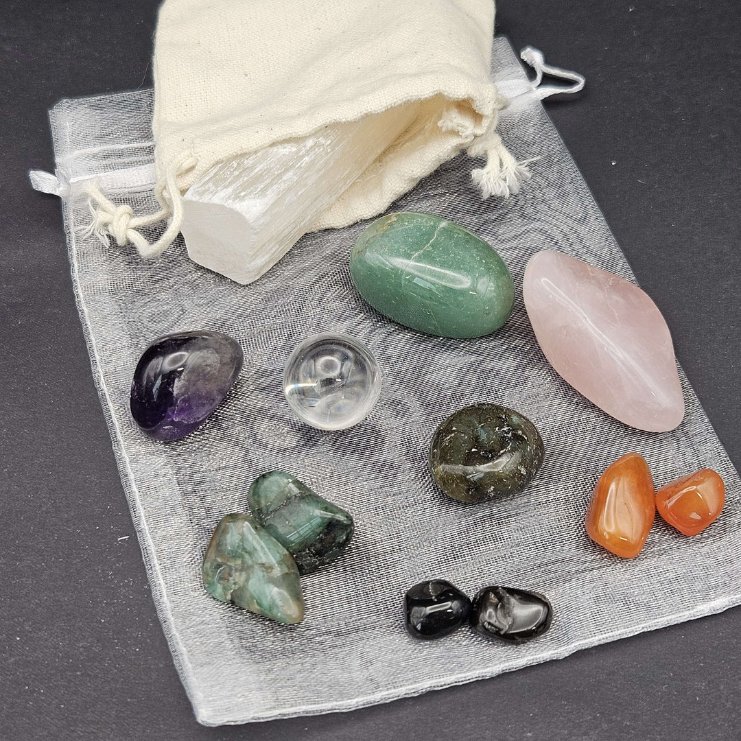 A beautiful flat-lay perspective of a beginner-friendly crystal starter pack featuring diverse multi-coloured tumbles. The natural stones rest on a grey protective organza layout, serving as a perfect spiritual gift set for wellness lovers. 