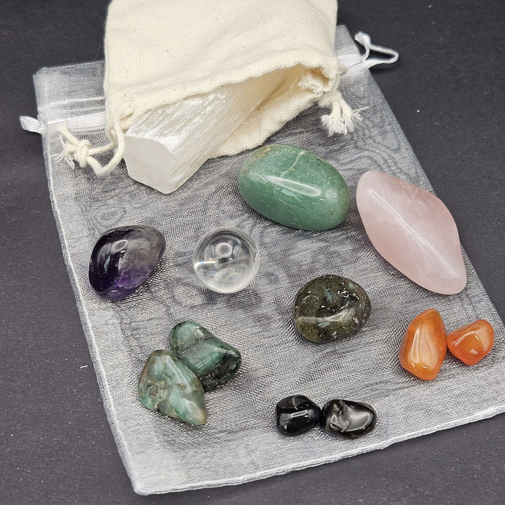 A beautiful flat-lay perspective of a beginner-friendly crystal starter pack featuring diverse multi-coloured tumbles. The natural stones rest on a grey protective organza layout, serving as a perfect spiritual gift set for wellness lovers. 