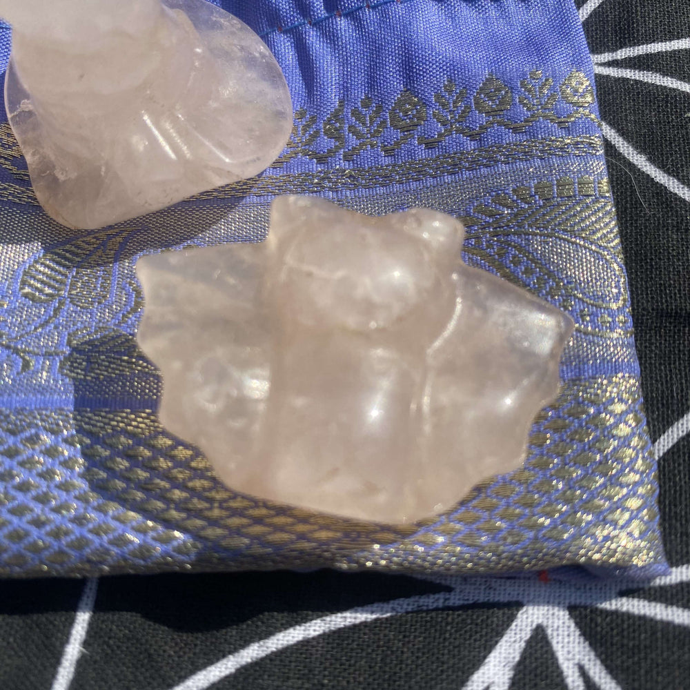 Angled overhead view of the translucent pink crystal bat and hat edge on the patterned gift bag in bright natural daylight
