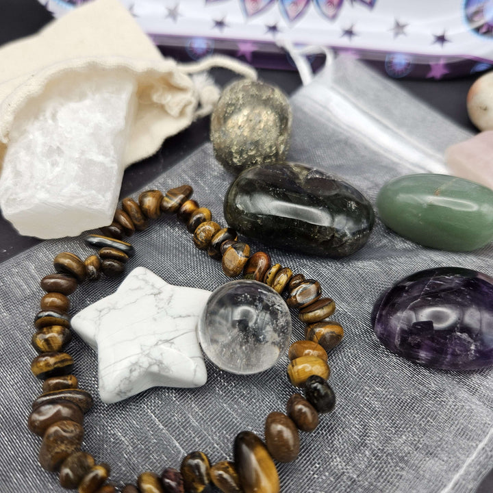 A detailed shot of a polished brown tiger eye stretch bracelet placed next to a raw metallic pyrite chunk and a white howlite star. This rich arrangement demonstrates how the grounding elements help realign the Solar Plexus and Root chakras. 