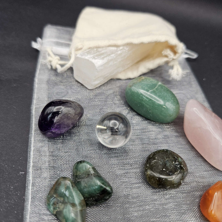 A detailed view of a tumbled gemstones kit showcasing green aventurine, pink rose quartz, and golden tiger eye. The crystals rest on a grey cloth, ready to act as a steady companion on a sunlit windowsill or quiet meditation altar. 
