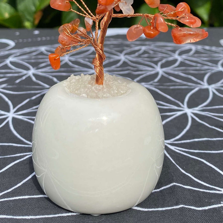 A close‑up shot highlighting the solid, round white quartz matrix chunk that acts as the heavy supporting base for the wire crystal tree trunk on a patterned altar display.