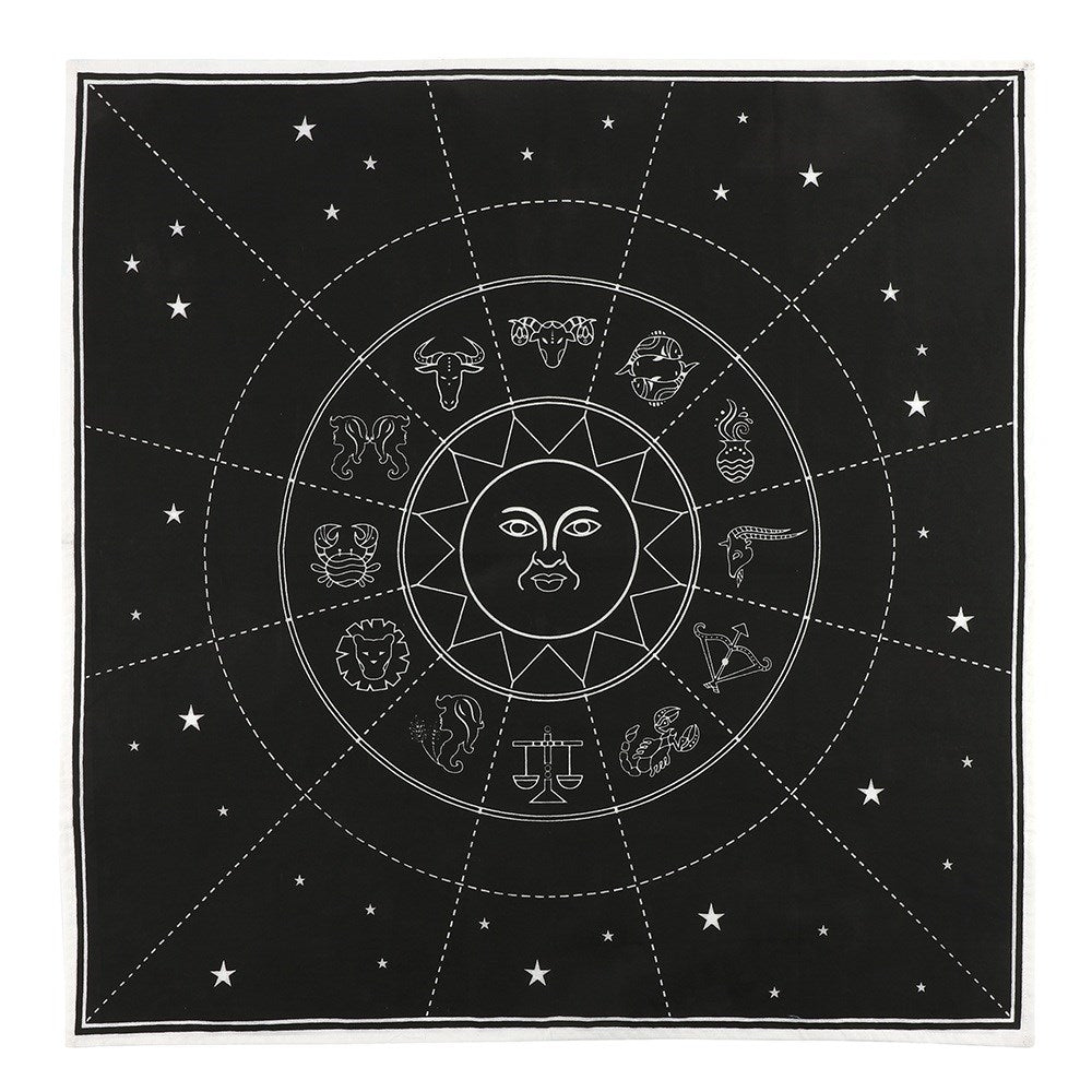 A black cotton altar cloth with a white zodiac chart design, displayed on a wall with candles and crystals.