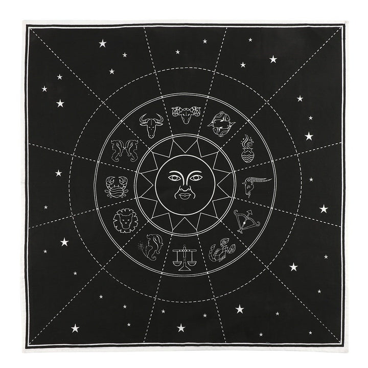 A black cotton altar cloth with a white zodiac chart design, displayed on a wall with candles and crystals.