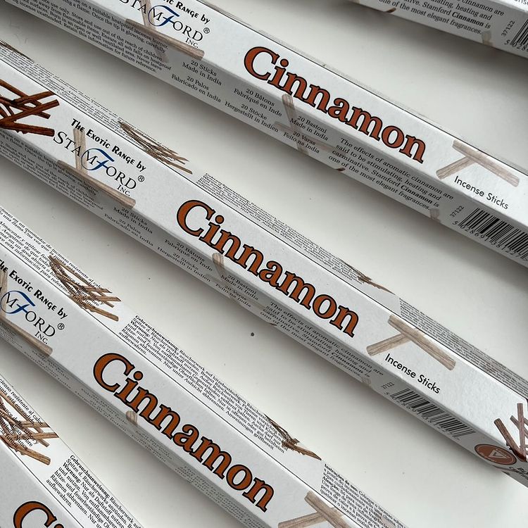 A collection of white incense sticks labeled 'Cinnamon' by Stamford, arranged diagonally on a white surface.