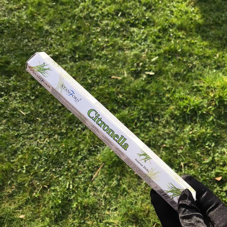A pack of Stamford Citronella incense sticks held against a grassy background.