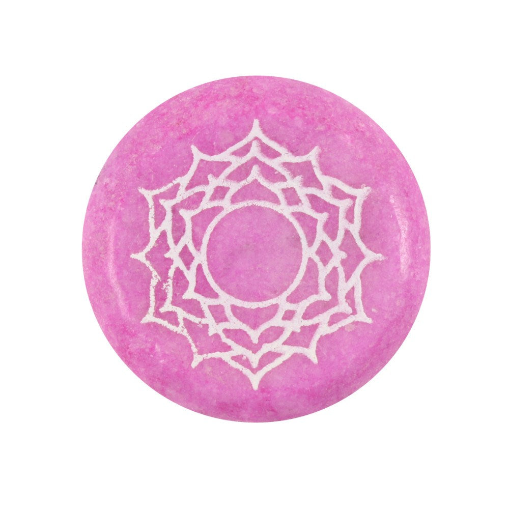 A pink polished stone with the crown chakra symbol engraved on it, used for meditation and manifestation.