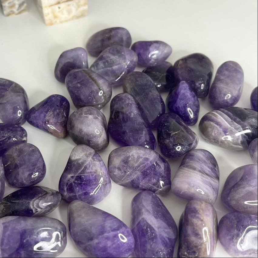 A pile of Dream Amethyst Tumble Stones in a bright sunlit office