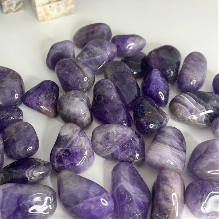 A pile of Dream Amethyst Tumble Stones in a bright sunlit office