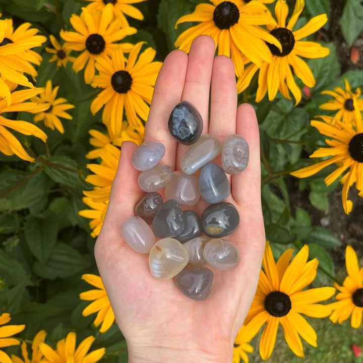 A handful of polished grey agate tumble stones held in a person&