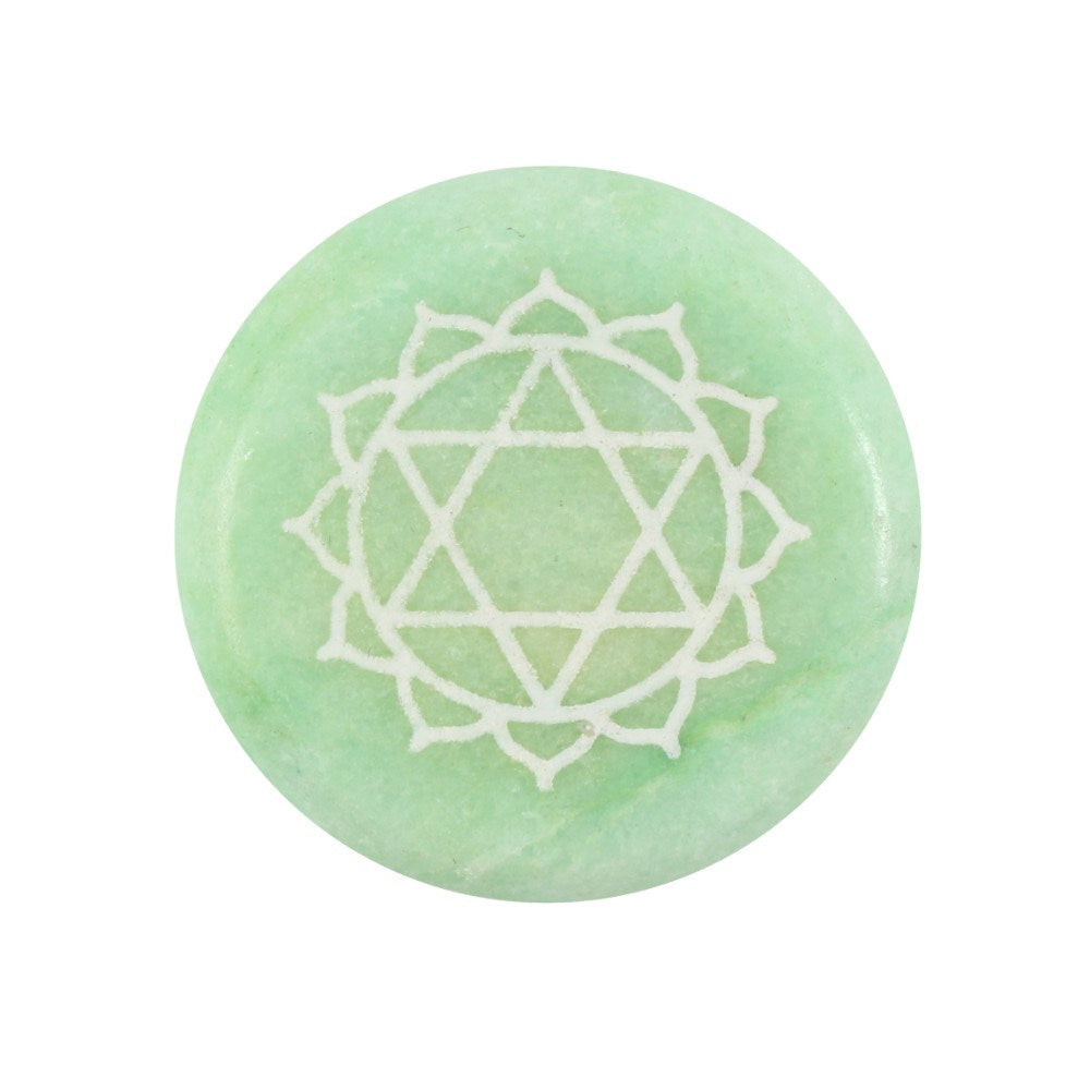 A circular, smooth light green crystal meditation stone engraved with the sacred Heart chakra symbol (Anahata) detailed in a white finish.