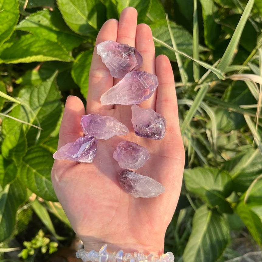 Mini Amethyst Rough Irregular Points being held in a hand in a garden on a bright sunny day