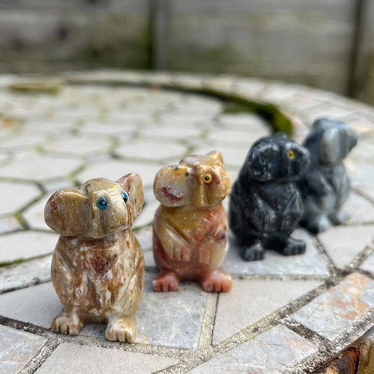 Three mini soapstone koalas in different colours placed on a tiled surface.
