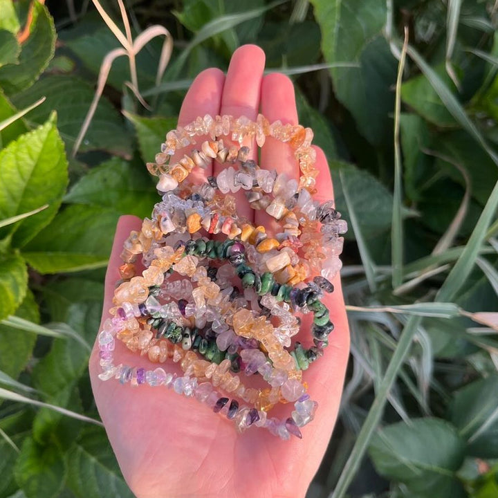 A pile of multi-coloured crystal chipped bracelets held in a person&