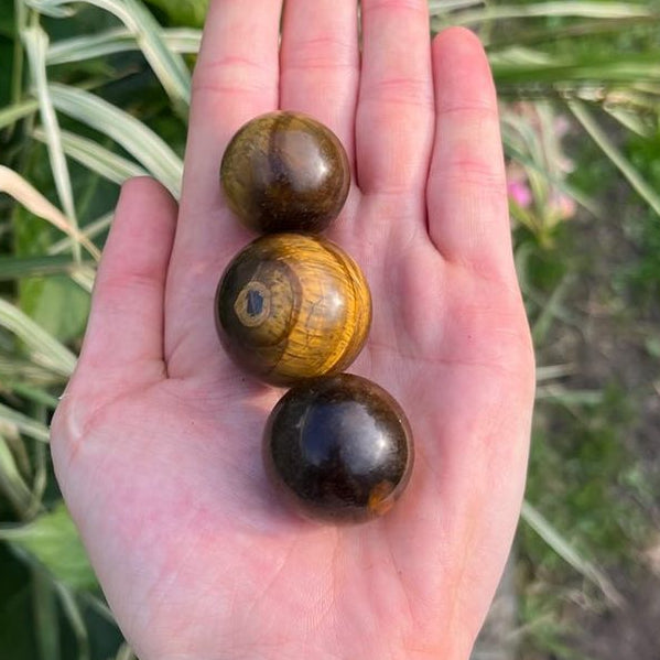 Three tiger eye crystal spheres held in a person&