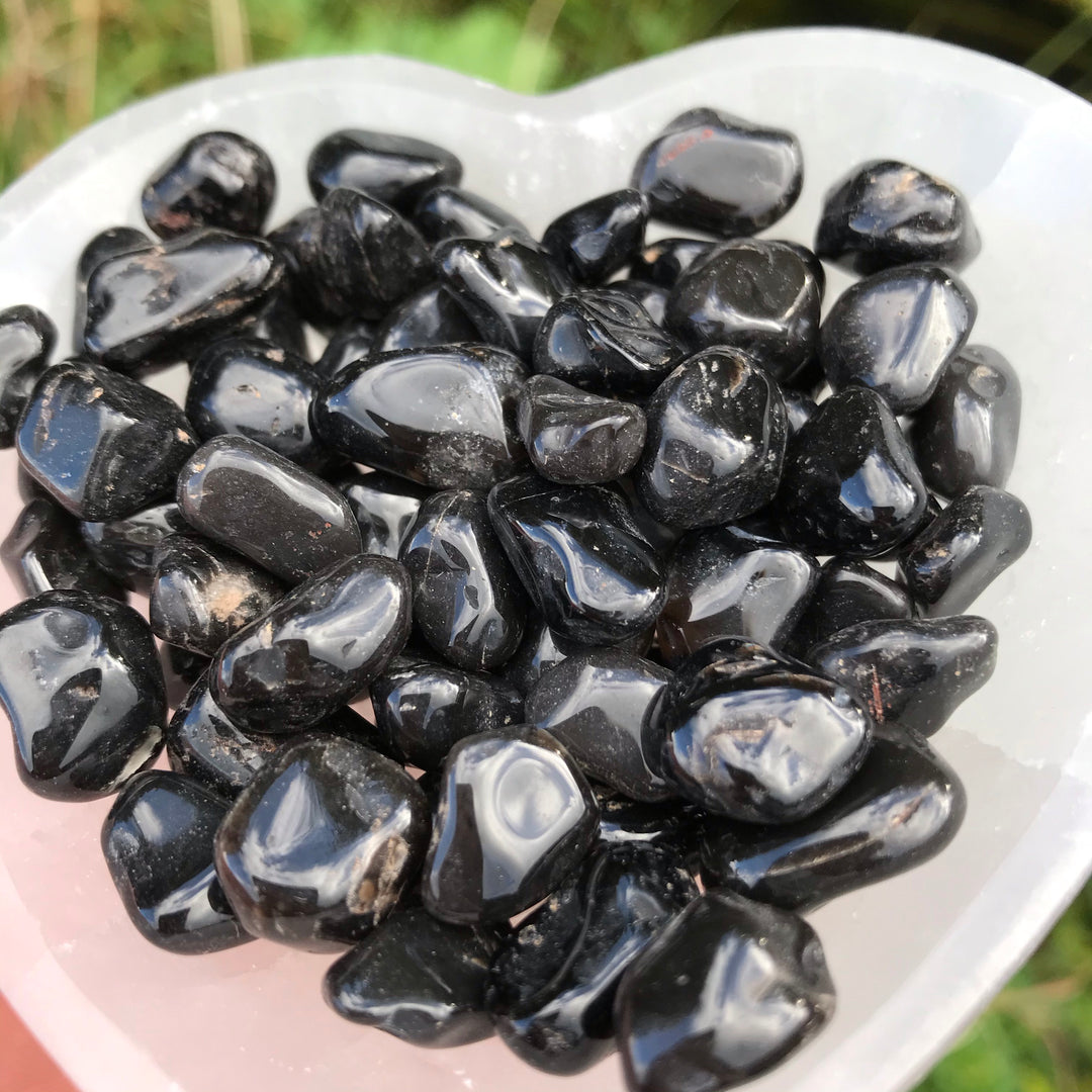 A pile of Tiny Black Onyx Tumble Stones in a heart shaped bowl