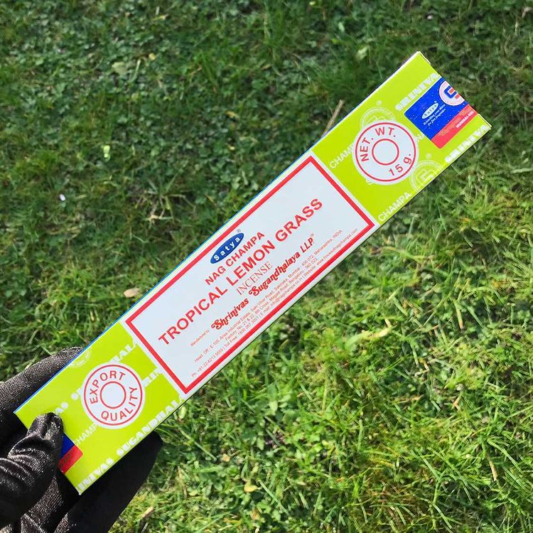 A pack of Tropical Lemon Grass incense sticks by Satya, held on a grassy background.