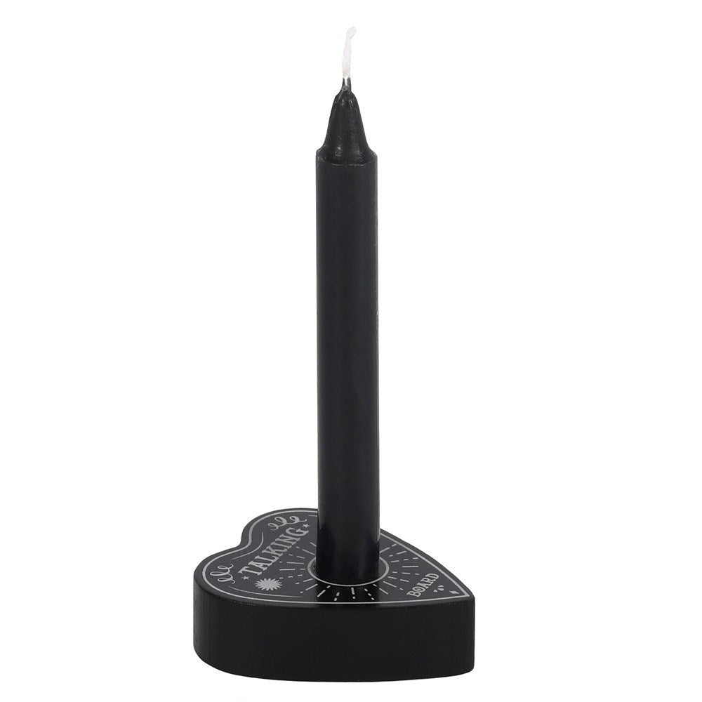 A side profile view showing a compact black planchette taper stand resting against a simple white backdrop. The lightweight holder securely cradles a slim, upright black ritual spell candle within its central slot, highlighting its functional design for a cosy evening meditation or manifestation practice.
