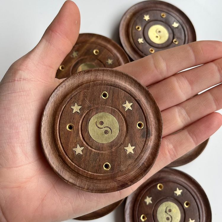 A close-up view of an open hand holding a single, polished circular Sheesham wood incense burner plate indoors. The perspective highlights the compact 7.5cm pocket scale, silky smooth finish, and brilliant metallic gold balance inlay to emphasize its portable design for a cosy bedroom altar setup.