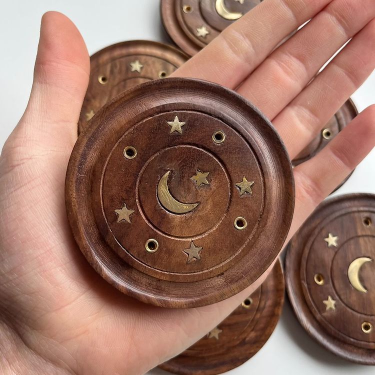 A close-up view of an open hand holding a single, polished circular Sheesham wood celestial incense burner plate indoors. The perspective highlights the compact 7.5cm pocket scale, smooth raised border contours, and bright metallic gold star inlays to emphasize its portable design for a cosy bedroom altar setup.